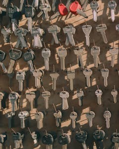 A collection of assorted metal keys hanging on a wall with hooks, casting shadows.